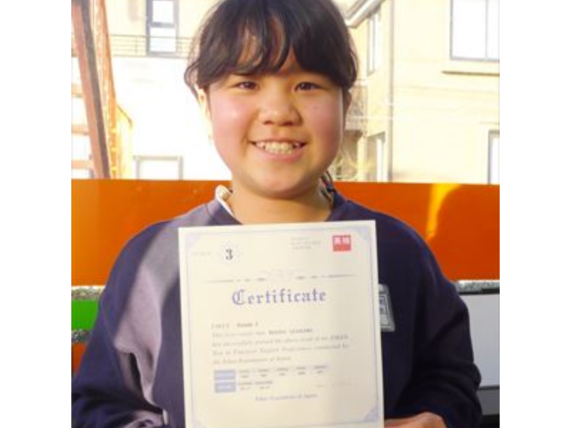 英検合格証を手にして喜ぶ小学生クラスの生徒